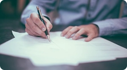 Close-up van een professional die papierwerk invult en documenten ondertekent met betrekking tot zakelijke, juridische of financiële diensten.